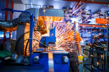 Metal ürünlerinin endüstriyel üretiminde kaynak makinesi üzerinde çalışan erkek bir tamirci. Parçaların altından kıvılcımlar çıkıyor. Konsept tema onarımı, mekanik, üretim, endüstri. Tanımlanamayan yüz