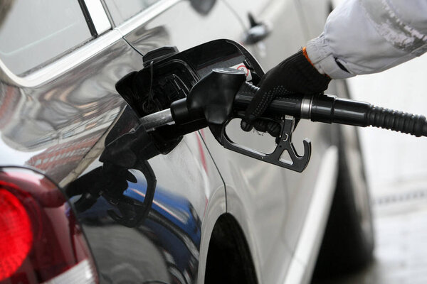 Hand holding fuel nozzle to add gas. Car refueling on a petrol station. Fuel, energy, ecology concept.