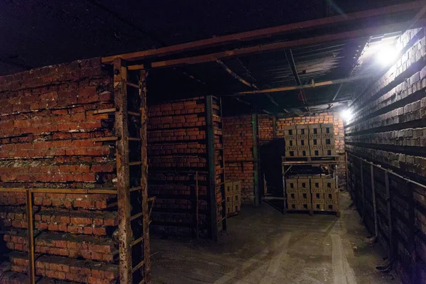 Production of clay bricks at a brick factory. Molded dried bricks stacked on pallets are load to the kiln for firing.