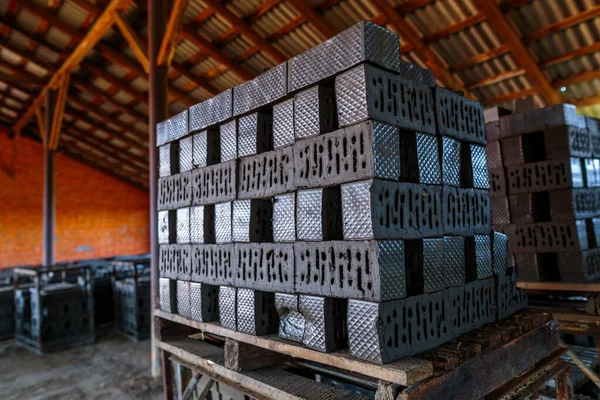 Production of clay bricks at a brick factory. Molded bricks stacked on pallets are dried before being sent to the kiln for firing.
