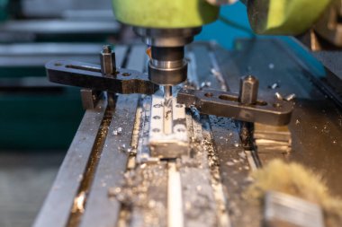 Çalışma sürecinin endüstriyel bir değirmen makinesinde yürütülmesi. Metal kısım kolona kenetlenmiş. Kesici boylamsal bir oyuk oluşturuyor. Soğutucu tedarik edildi. Metal talaşları kenarlara doğru uçar..