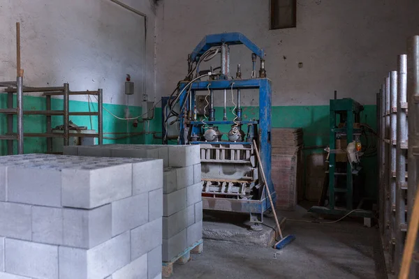 Industrial production of building cement pressed materials. High quality hollow concrete block or cement brick and hydraulic press. Finished products stacked on pallets dry after the press.