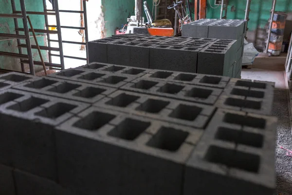 Industrial production of building materials from pressed cement mortar. High quality hollow concrete block or cement brick. Finished products stacked on pallets dry after the press.