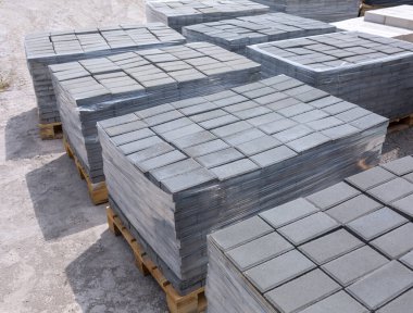 Baskılı çimento harcından endüstriyel yapı malzemeleri üretimi. Kaliteli kaldırım taşları. Filme yüklenmiş paletler üzerindeki bitmiş ürünler gönderilmeyi bekliyor.