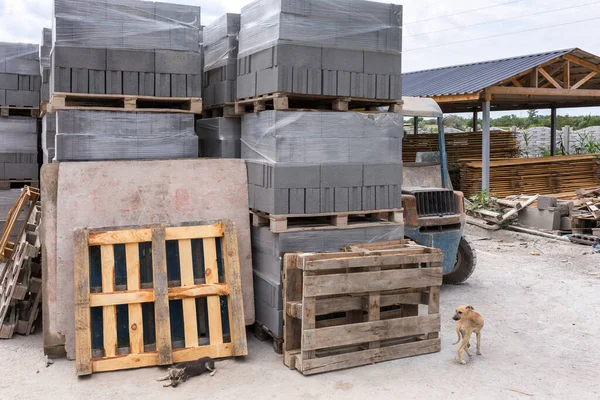 Industrial production of building cement pressed materials. High quality hollow concrete block or cement brick and paving stones. Finished products on pallets packed in film are waiting to be shipped.