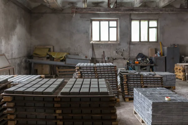 Industrial production of building materials from pressed cement mortar. High quality paving stones made of high quality cement. Finished products stacked on pallets dry after the press.