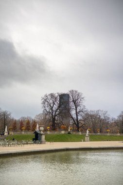 Paris 'teki Lüksemburg Bahçesi' nin sonbahar manzarası. Montparnasse Tur gökdeleni çıplak ağaçların ve büyük göletin arkasında görülebilir..