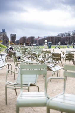 Lüksemburg Bahçeleri, Paris, Fransa 'da çakıl yolunda birden fazla açık yeşil metal sandalye. Bulutlu bir sonbahar gününde arka planda tanınmayan insanlar görünür..