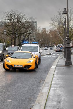 Paris, Fransa - 4 Aralık 2021: Polis memurları, Pont de Sully köprüsünde bir McLaren 12C spor arabadaki bir sürücünün önyargılı belgelerini kontrol ettiler. Diğer arabalar ve bir otobüs arka planda bulutlu bir yerde.
