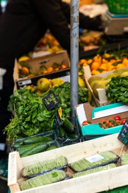 Salatalık, armut ve portakallar da dahil olmak üzere taze sebzeler bir sokak pazarında tahta kasalarda satılıyorlar. Ön planda 