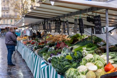 Fransa 'nın Paris kentindeki bir sokak pazarında karnabahar, pırasa, enginar, turp, lahana, romanesko lahana ve lahana gibi taze sebzeler satılıyor. Arka planda bir satıcı var..