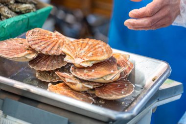 Taze deniz tarakları Fransa 'nın Paris kentindeki bir deniz ürünleri pazarında metal bir tepside. Arka planda bir satıcı var. Kabukları turuncu ve kahverengidir..