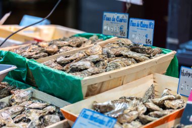 Paris, Fransa - 4 Aralık 2021: Fines de Claires 'in yerel Fransız istiridyeleri bir sokak pazarında satılıktır. İstiridyeler ahşap sandıkların içinde Fransızca işaretlerle sergileniyor..