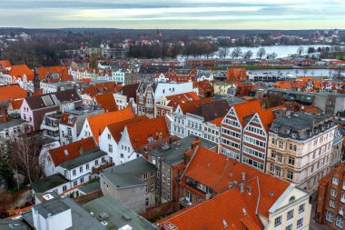 Almanya 'nın kuzeyinde Schleswig-Holstein eyâletinde, ortaçağ Lubeck' inin batı kısmının görüntüsü. Fotoğrafta terracotta çatısı ve arkasında Trave Nehri olan eski binalar var..