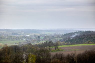 Nisan ayı sonlarında Ukrayna 'nın Cherkasy bölgesindeki Vilshanka Nehri vadisinde Mliyiv köyü manzarası. Yeşil tarlalar ve yuvarlanan tepelerle çevrili evler ve binalar..