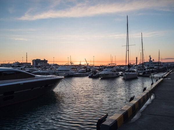 Морской пирс с яхтами вечером на закате в Сочи
