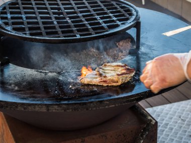 Cook Soçi'de dairesel bir ızgara üzerinde kaburga hazırlar