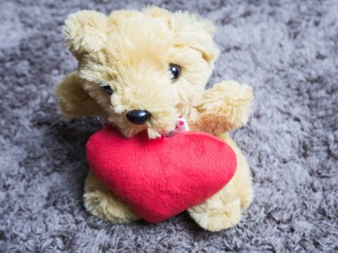 Halıüzerinde oturan bir kalp ile yumuşak oyuncak kabarık ayı