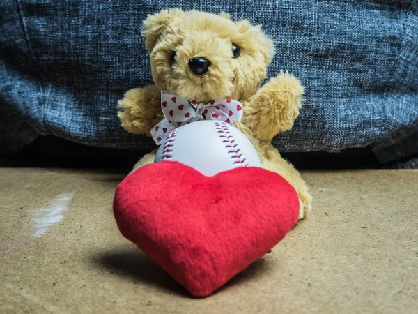 Oyuncak ayı bir beyzbol ve kırmızı bir kalp ile oturur — Stok fotoğraf
