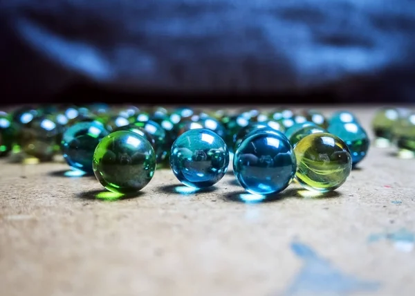 Bolas de vidrio de colores esparcidas sobre una superficie de madera —  Fotos de Stock