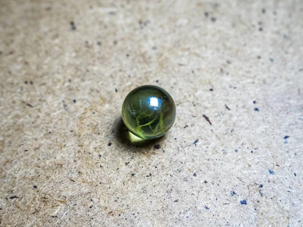 En grön glas sfär på en träyta och kaustik — Stockfoto
