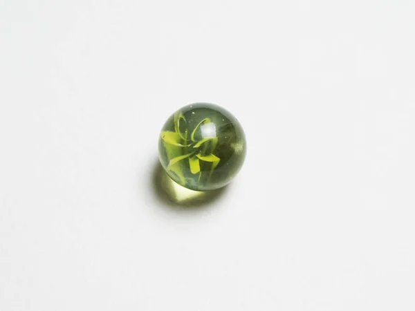 Uma bola de vidro verde com cáustico em um fundo branco — Fotografia de Stock