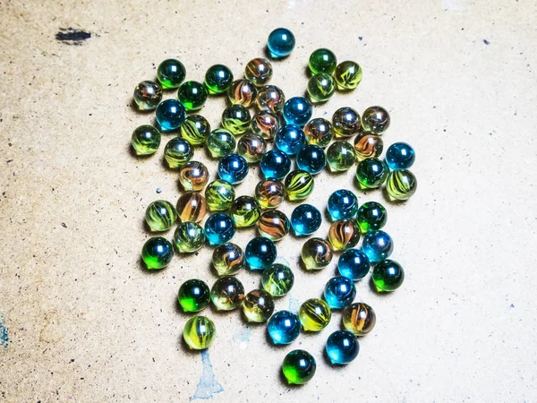 Bolas de vidro coloridas espalhadas em uma superfície de madeira — Fotografia de Stock