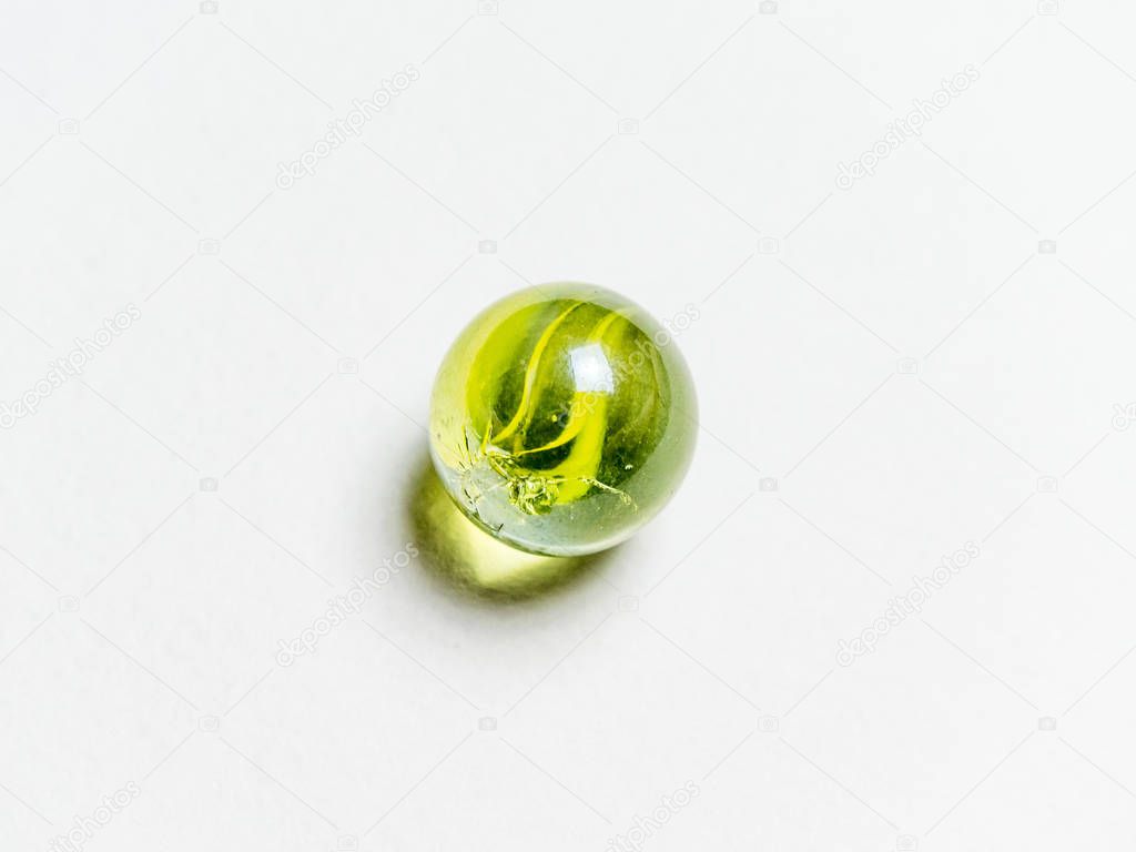 One green glass ball with caustic on a white background