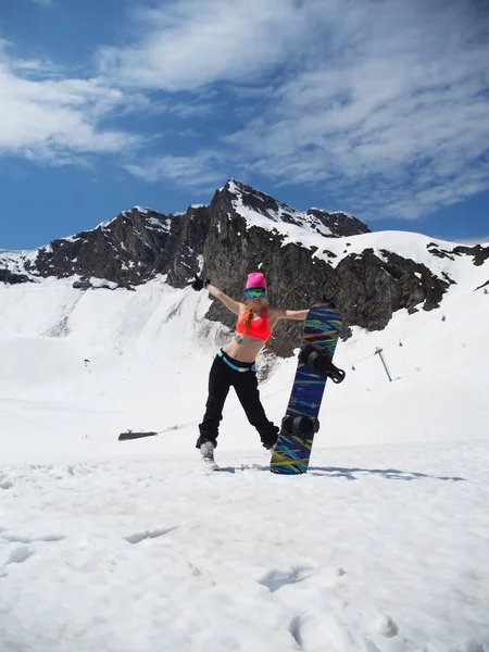 スキー場ゴーリキーゴロドの山々を背景にスノーボードでポーズをとる美少女スノーボーダー。ロシアソチ 05.11.2019 — ストック写真