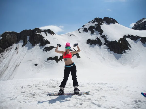 Bonita menina snowboarder posando mostrando o poder dos bíceps contra o fundo das montanhas na estância de esqui Gorki-Gorod. Rússia Sochi 05.11.2019 — Fotografia de Stock