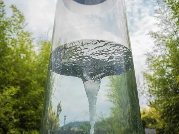 ガラスの円筒形フラスコの水は竜巻公園ソチを作成します — ストック写真