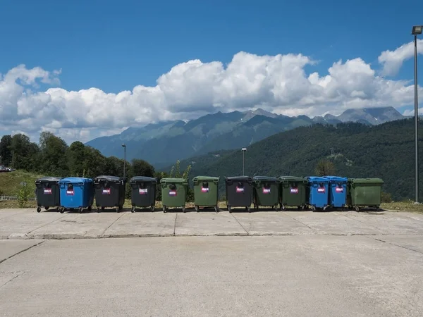 Many large garbage cans stand in a row against the backdrop beautiful mountains — Stock Photo, Image