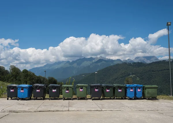Many large garbage cans stand in a row against the backdrop beautiful mountains — Stock Photo, Image