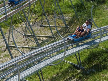 Baba ve oğul Rodelbahn'da yüksek hızda saça binerler. Rosa Khutor. Yükseklik 1100 m. Rusya Soçi 08 04 2019