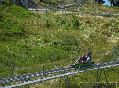 Rodelbahn'da anne ve kızı neşeli bir yolculuk. Rosa Khutor. Yükseklik 1100 m. Rusya Soçi 08 04 2019