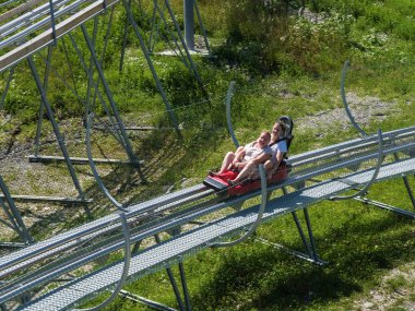 Rodelbahn'da anne ve kızı neşeli bir yolculuk. Rosa Khutor. Yükseklik 1100 m. Rusya Soçi 08 04 2019