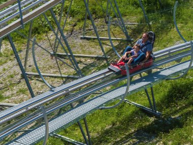 Baba ve oğul Rodelbahn'a biniyor. Rosa Khutor. Yükseklik 1100 m. Rusya Soçi 08 04 2019