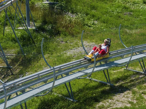Büyükanne ve torunu Rodelban geri yüksek hızda saç binmek. Rosa Khutor. Yükseklik 1100 m. Rusya Soçi 08 04 2019