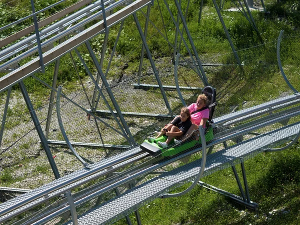 Mom and daughter joyful ride on Rodelbahn. Rosa Khutor. Height 1100 m. Russia Sochi 08 04 2019 — Stock Photo, Image