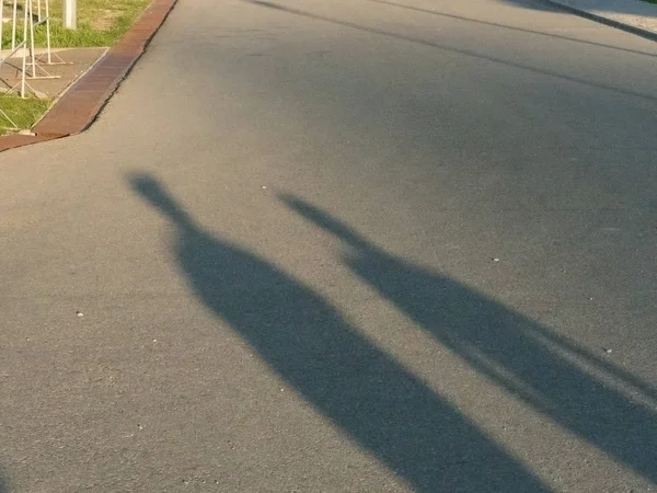 Sombra de duas pessoas na estrada de tarde — Fotografia de Stock