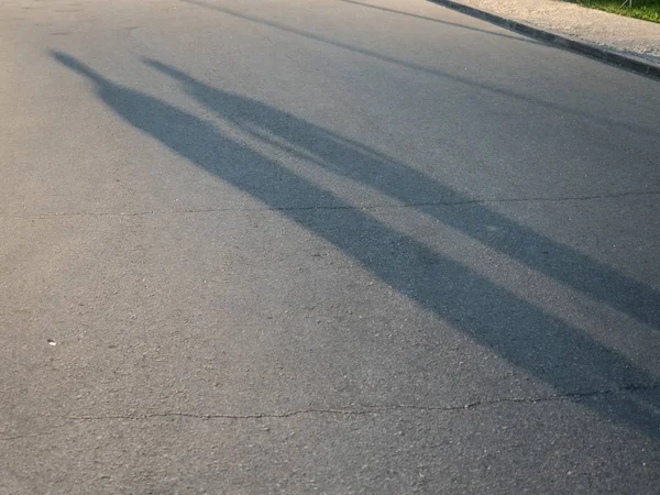 Schaduw van twee mensen op de weg in de avond — Stockfoto