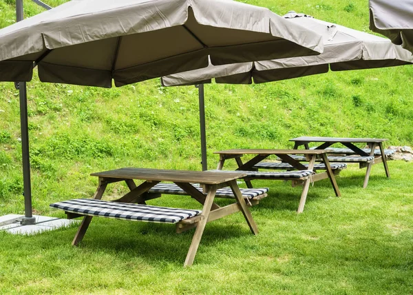 녹색 잔디에 큰 우산 아래 테이블 벤치 — 스톡 사진