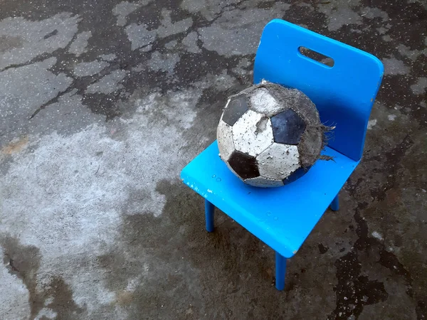 Una pelota de fútbol desaliñada yace en una silla para niños en el patio de la calle. Triste infancia —  Fotos de Stock