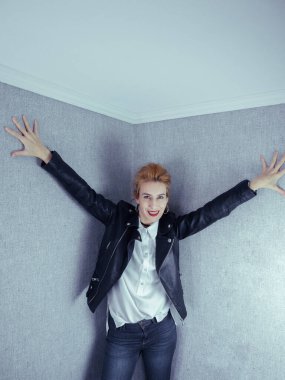 Siyah deri ceketli güzel kız ellerini gri duvar kağıdına koydu.