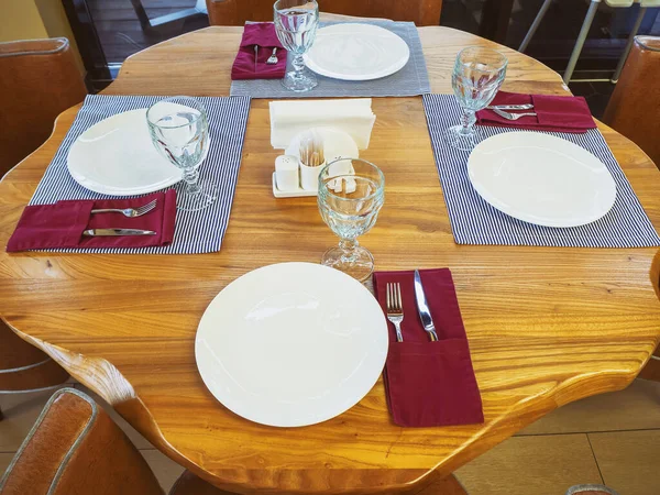 Gesneden ronde tafel met kristallen glazen, borden, servetten en zilverwerk. Tafelopstelling in een café — Stockfoto