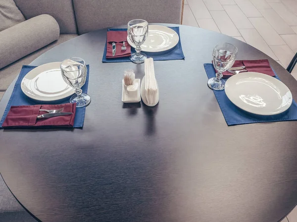 Ronde tafel met glazen, zilveren borden en servetten. Serveert voor drie personen. Close-up foto — Stockfoto