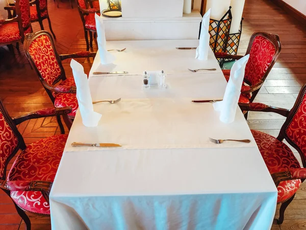 Rusland, Sotsji 14.03.2020. Een rechthoekige tafel met een wit tafelkleed en witte servetten erop en rode klassieke stoelen. Restaurant Interieur — Stockfoto