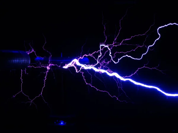 Bright white-blue electric lightning emanates from electric coils in the dark