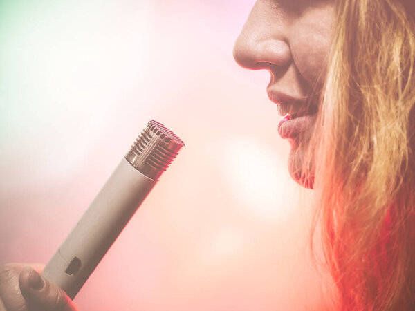 Фрагмент женского профиля со старым советским микрофоном во рту. Фото с розовым фильтром
