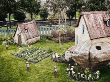 Rusya, Soçi 14.03.2020. Bahçede çiçekli iki küçük peri masalı ev. Fenerler arkada alçak çitler ve arka planda ağaçlar.